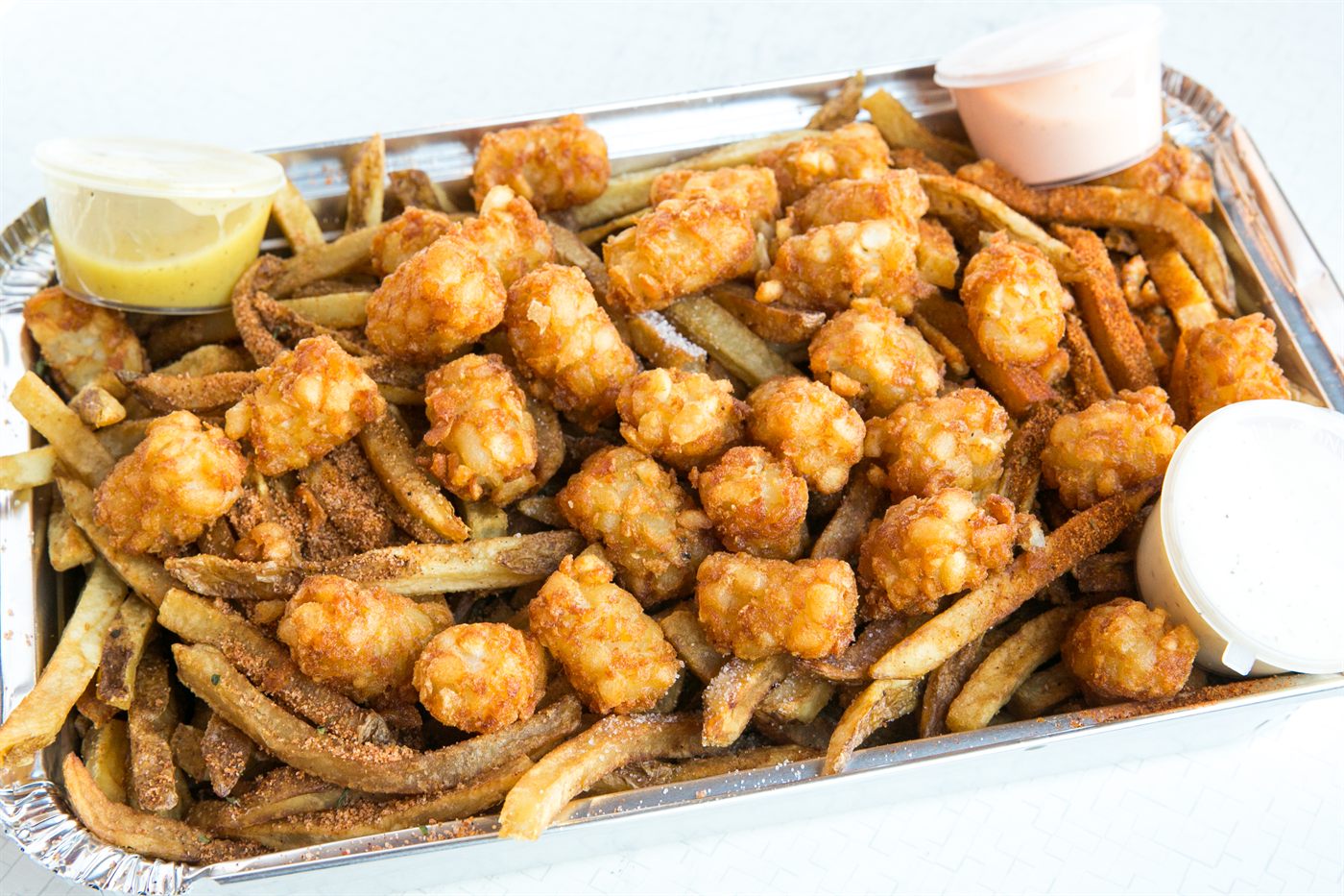 Seasoned fries and tater tots with dipping sauces